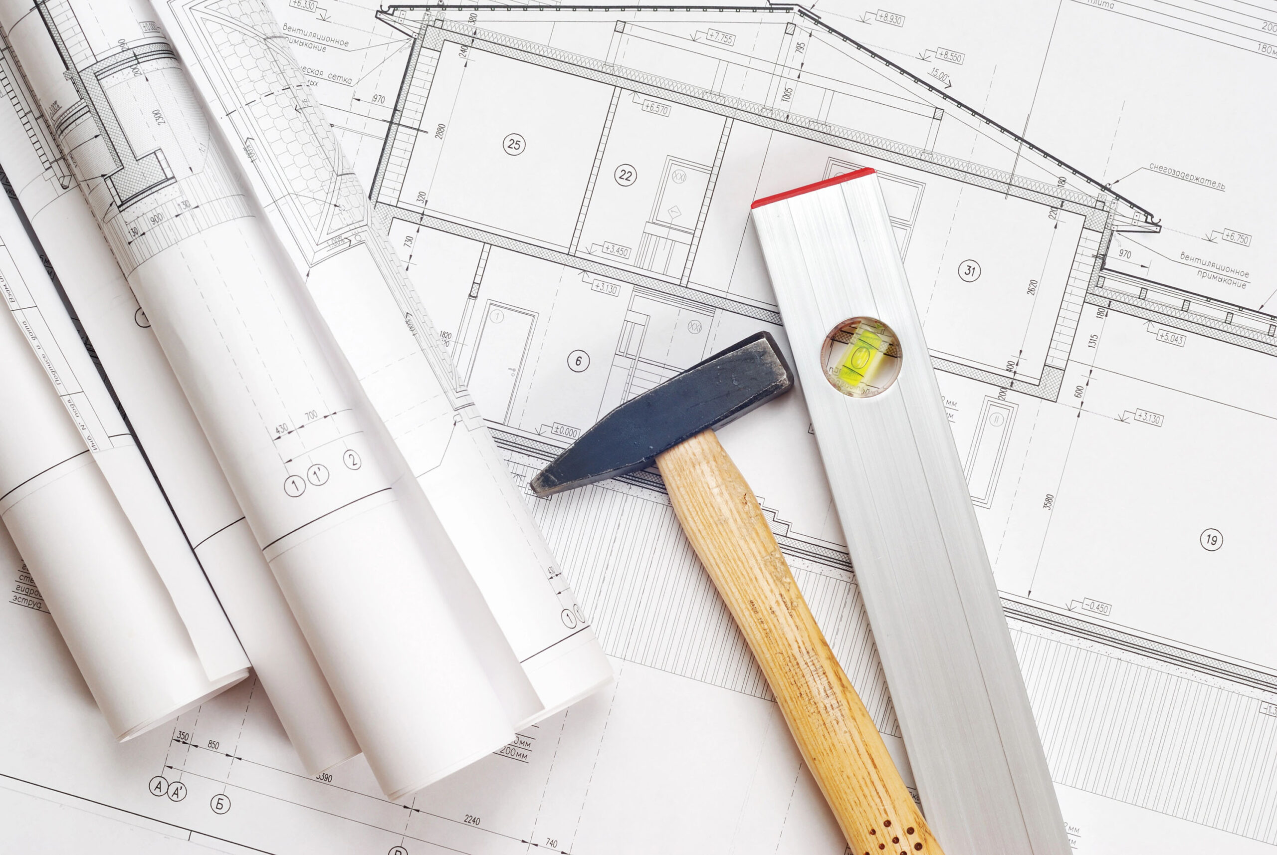 Architekturzeichnungen mit zusammengerollten BauplĂ€nen, Hammer und Wasserwaage â Symbolbild fĂŒr Bauplanung und Handwerk